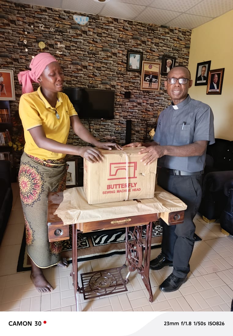 A young woman receiving a sewing machine through the VIN-JPIC livelihoods empowerment programme